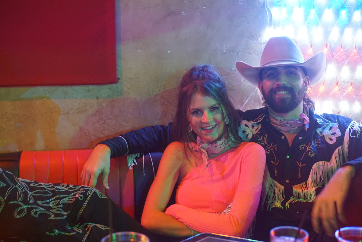 Two members of the HTT community beneath the lights of a honky tonk